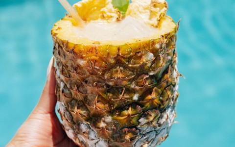 a hand holding a pineapple drink