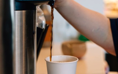 a person pouring a coffee into a cup