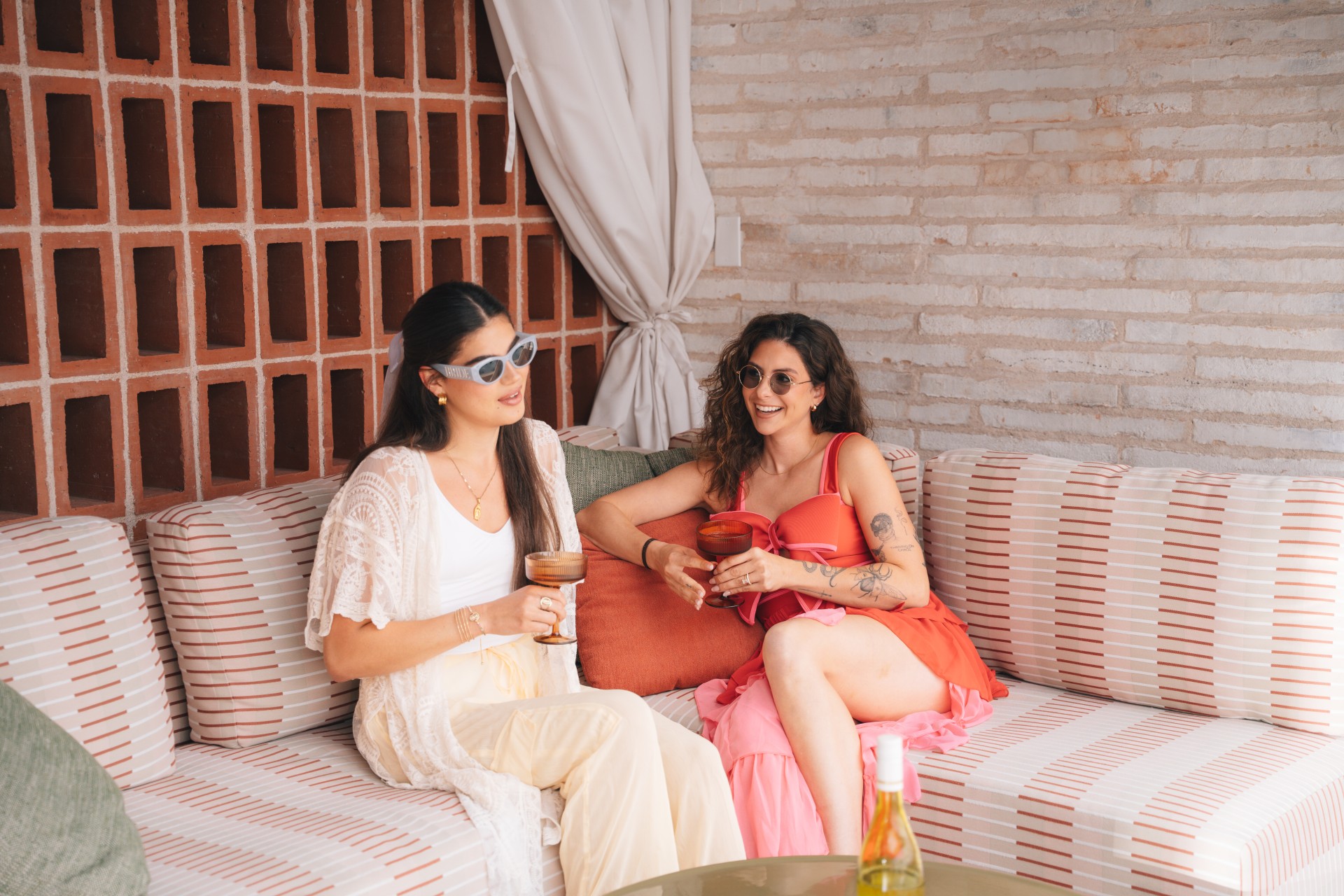 two women sitting on a couch holding drinks