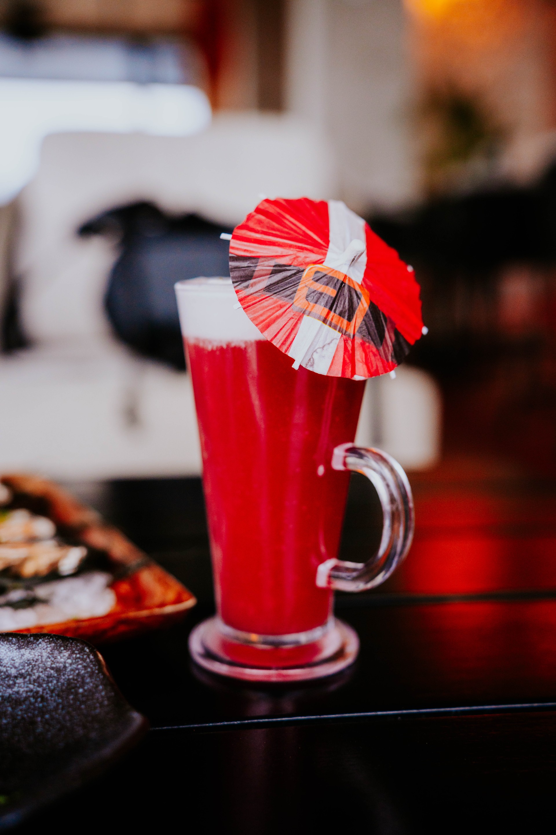 a glass of red liquid with a umbrella on top