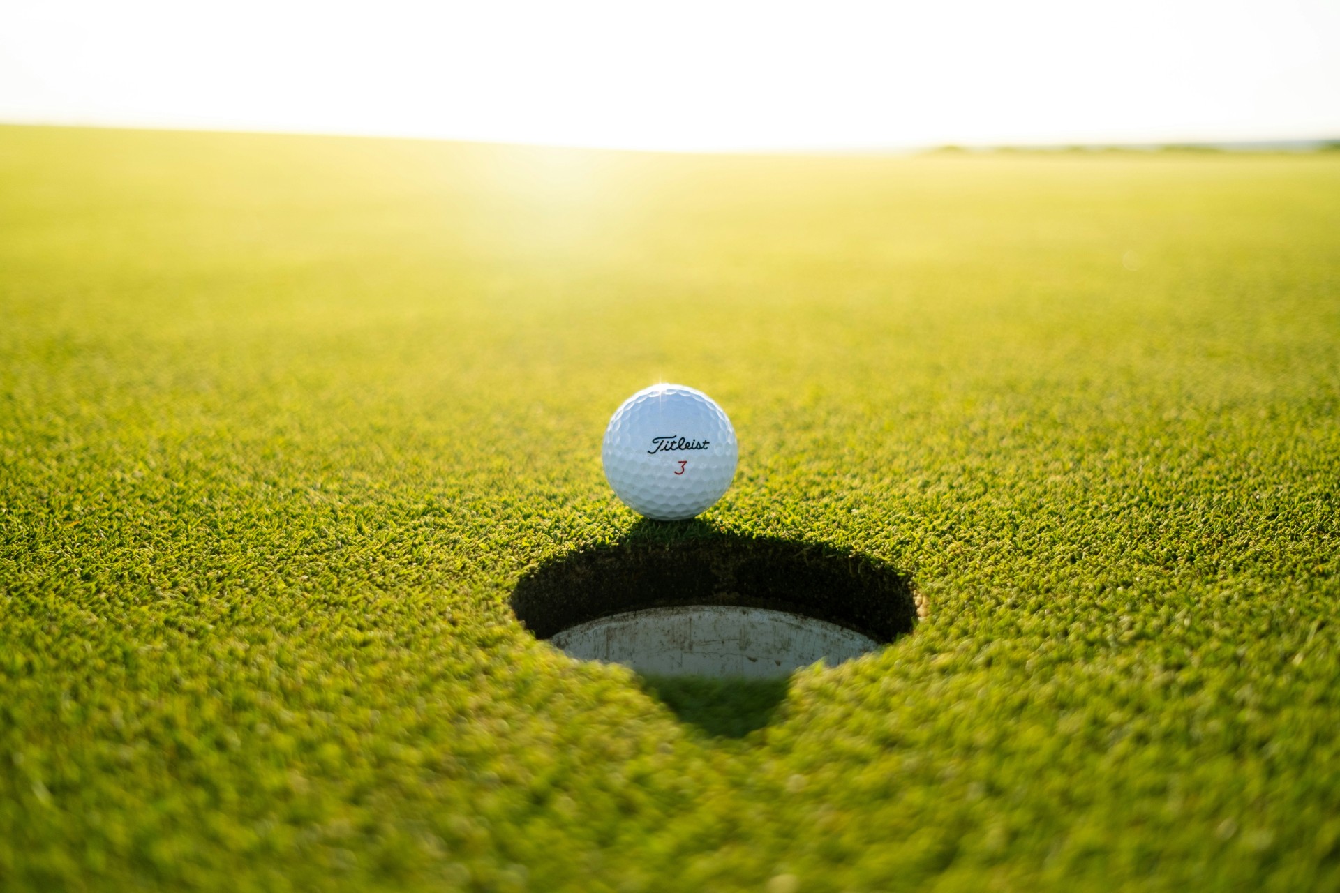 a golf ball on the edge of a hole