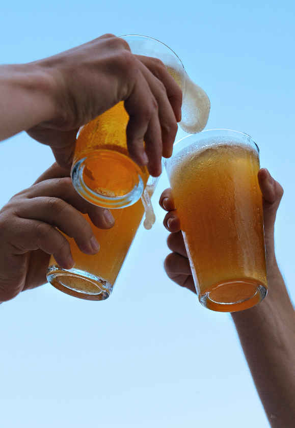 a group of hands holding glasses of beer