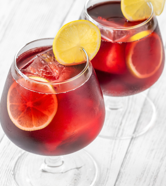 two glasses of red liquid with ice and lemon slices