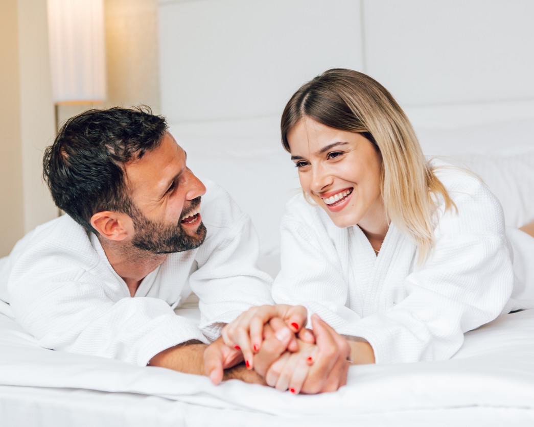 a man and woman in white robes lying on a bed
