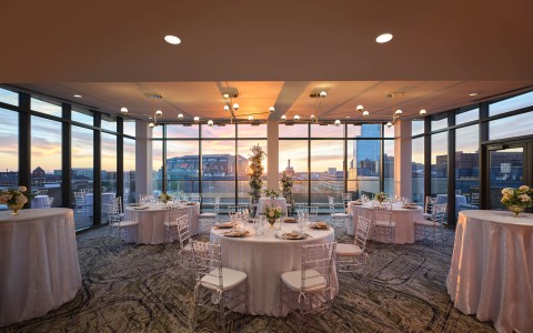 A close-up of a dinner table with clear chairs and flowers