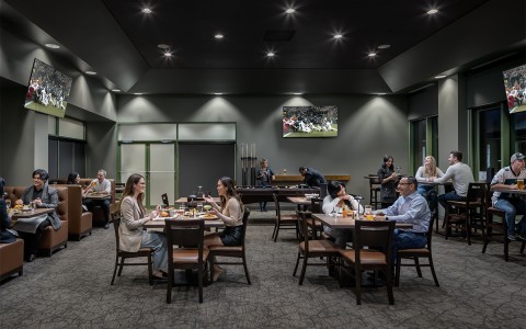 a group of people sitting at tables in a room with a television
