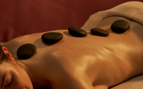 a woman lying on a bed with a stone on her back
