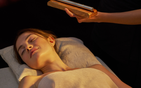a woman lying down on a bed with a stick over her head