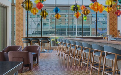 a room with chairs and a bar with colorful lanterns from the ceiling