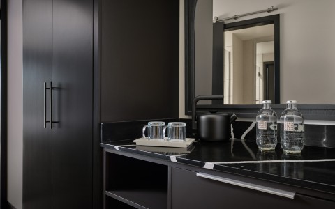 a black counter top with a black cabinet and two clear glasses on it