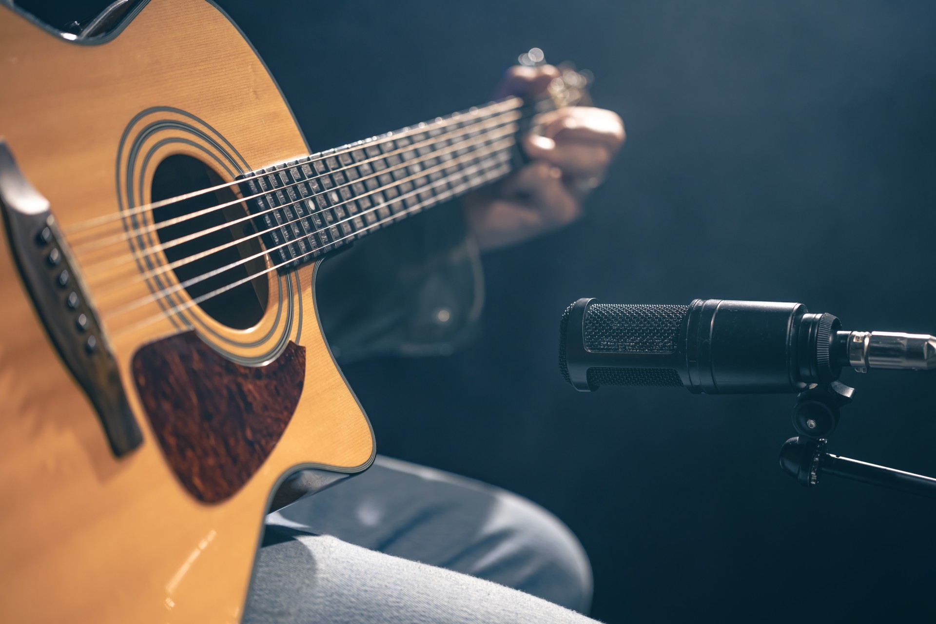 a person playing guitar and holding a microphone