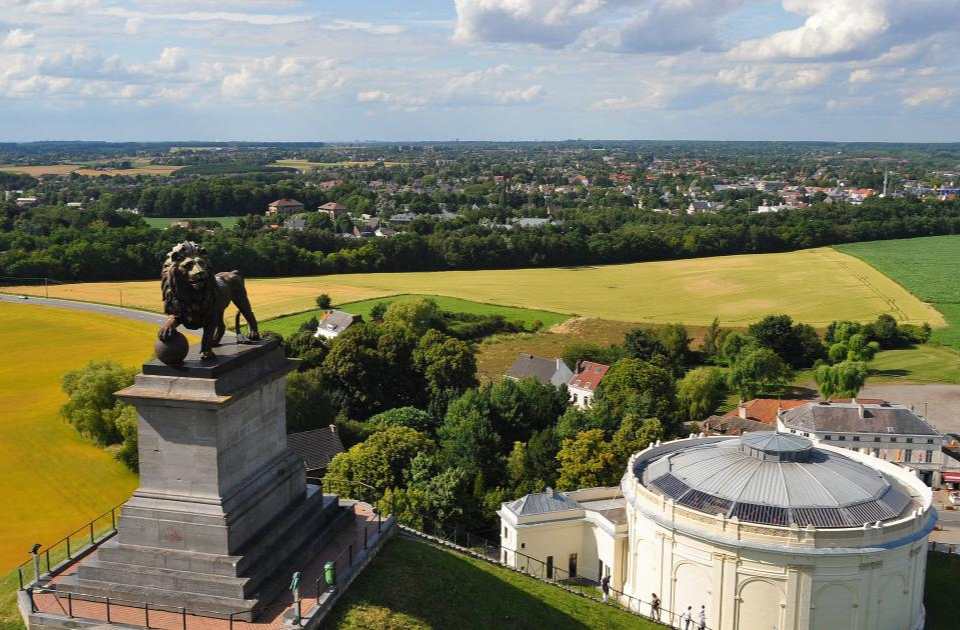 a statue of a lion on a pedestal with a circular building in the background