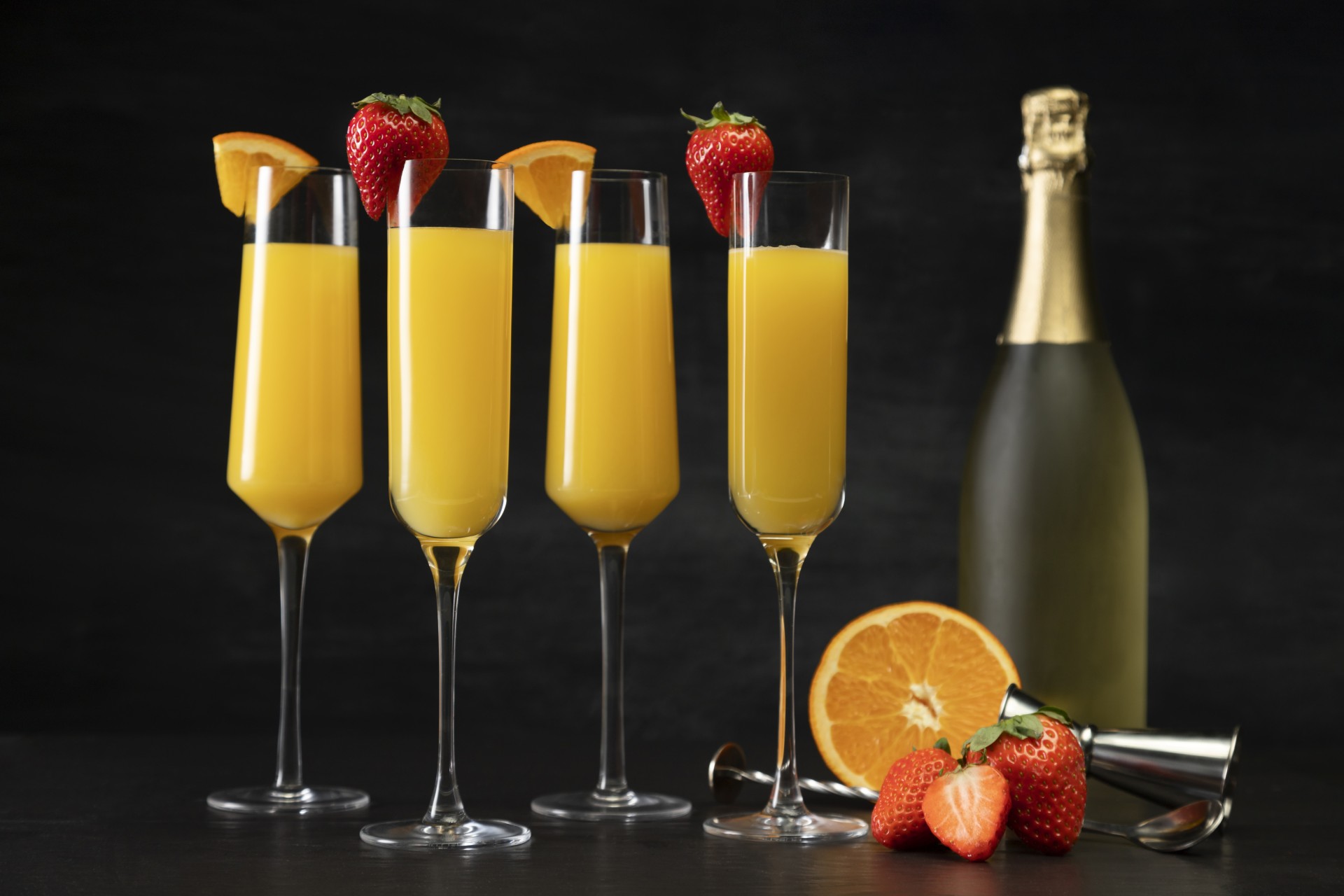 a group of glasses with orange juice and strawberries