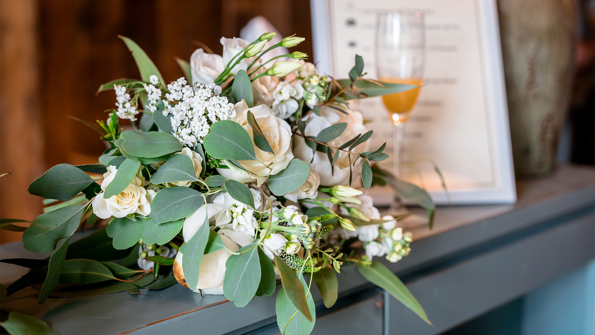a bouquet of white flowers and green leaves on a blue dresser