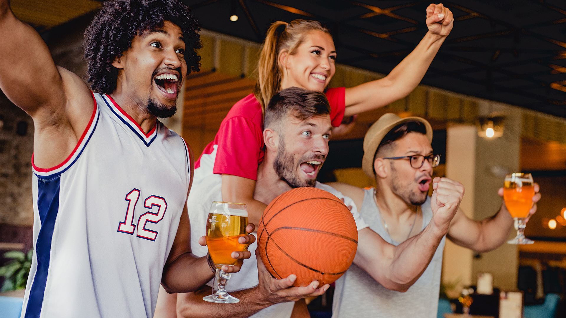 a group of people holding a basketball and a glass of beer