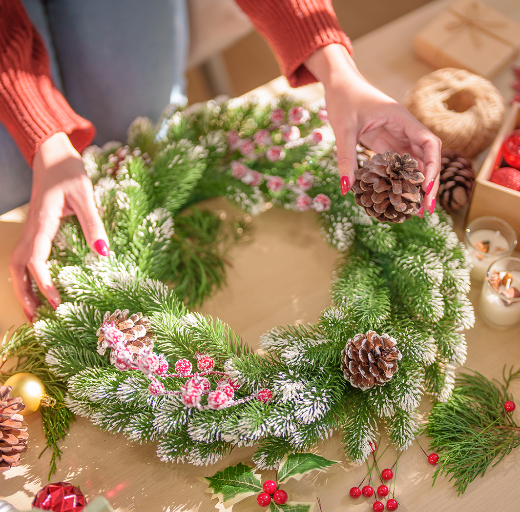 a person holding a pine cone and a wreath