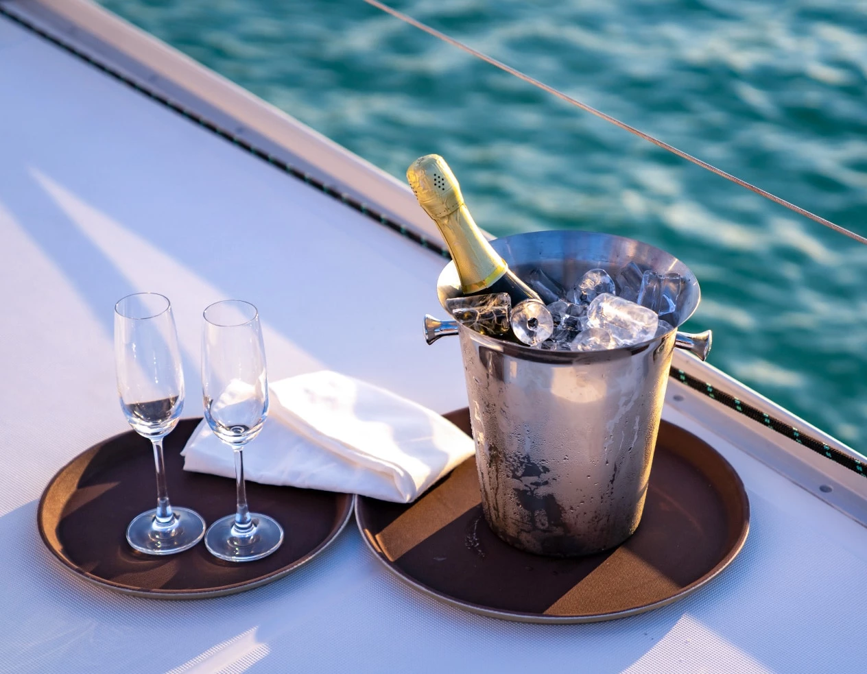 a metal bucket with a metal handle on a wooden surface by a body of water