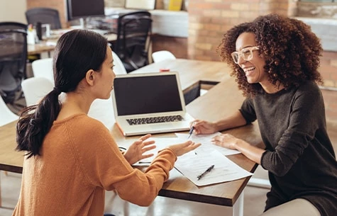 a woman showing a woman something on the laptop