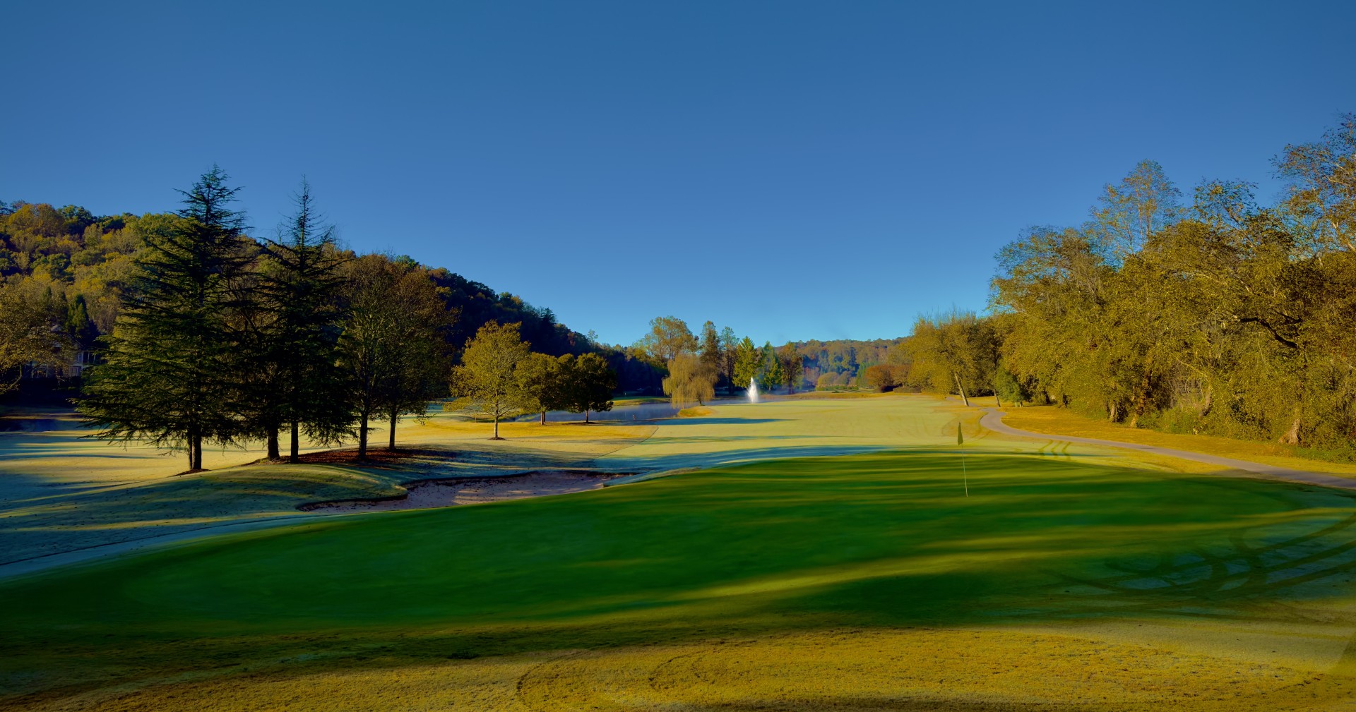 a golf course with trees and a fountain