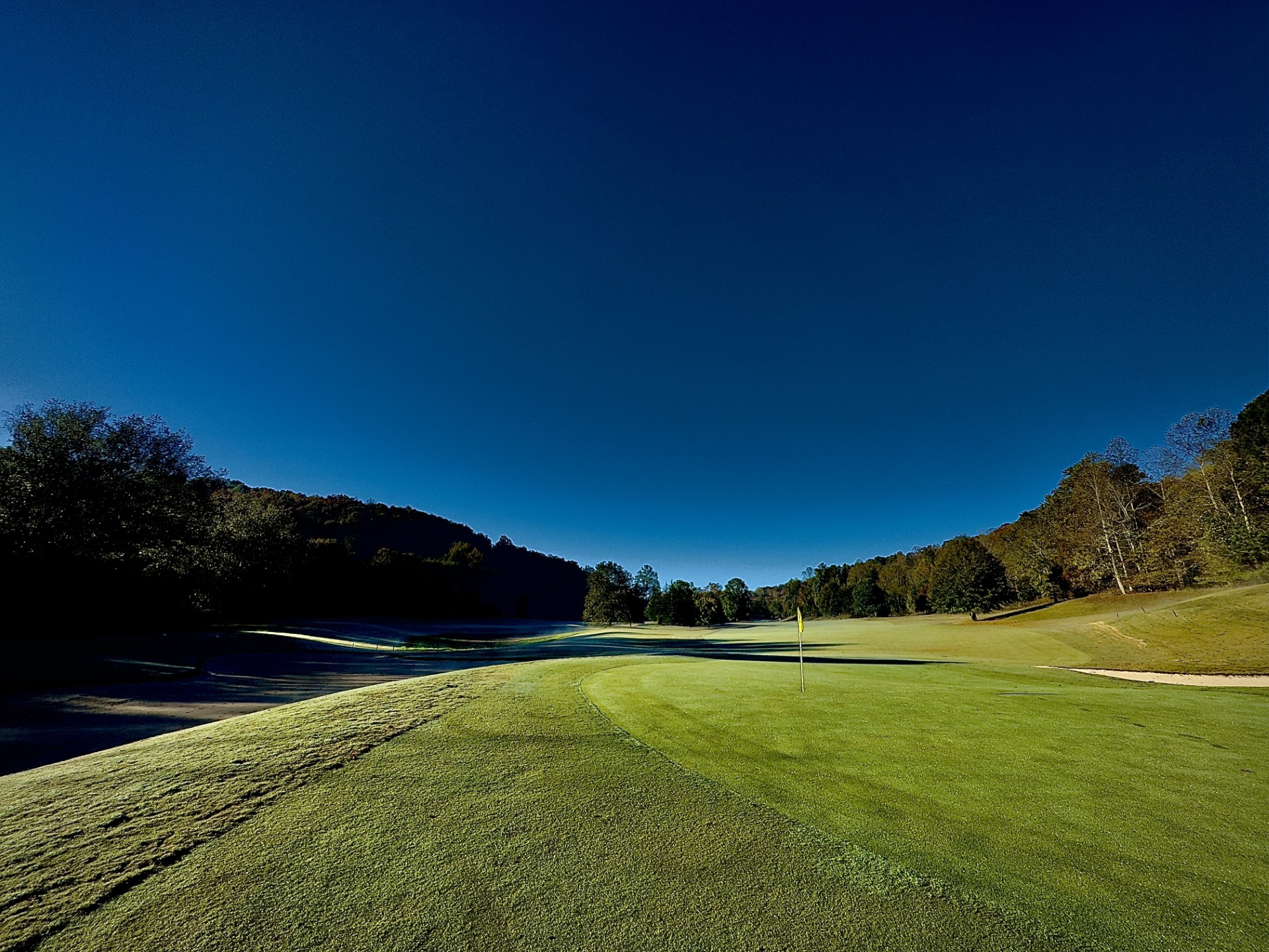 a golf course with trees and blue sky
