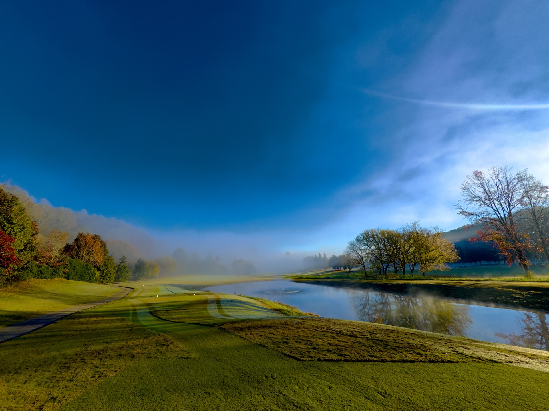 a golf course with a river and trees