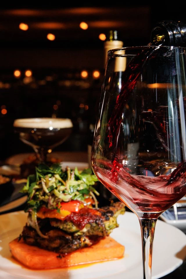 a glass of red wine being poured into a glass