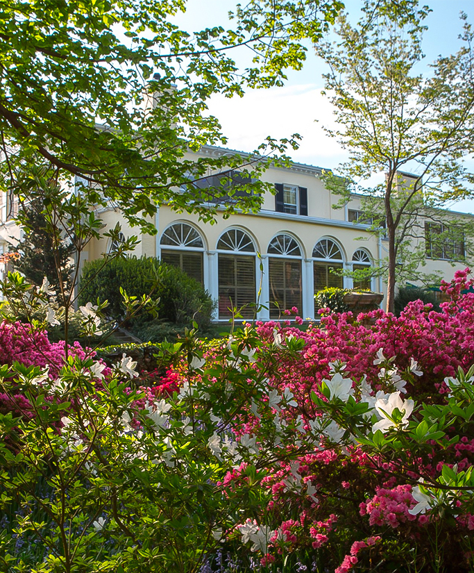 a building with many windows and flowers in front of it Next
