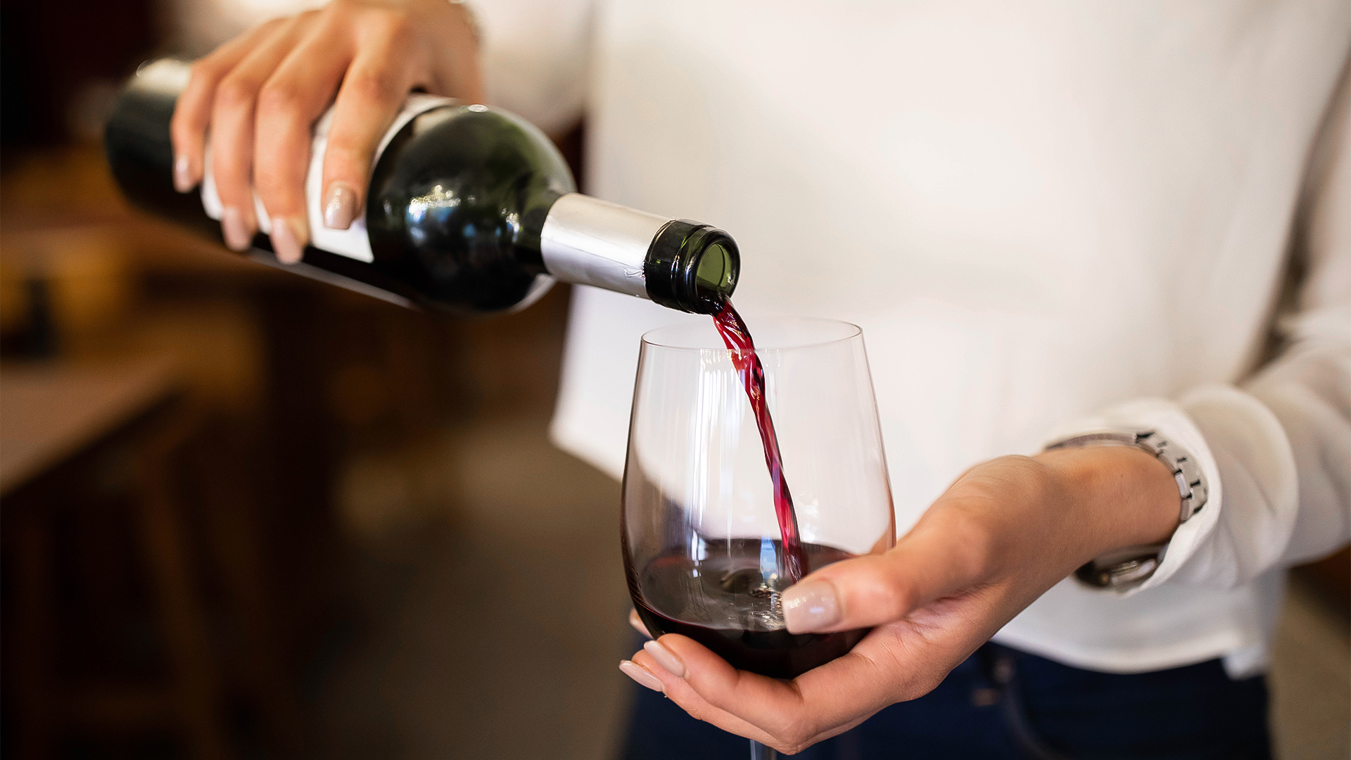 a person pouring a glass of wine