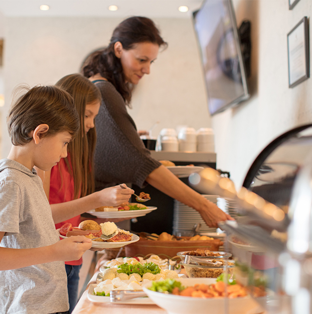 a woman and children standing next to a buffet table