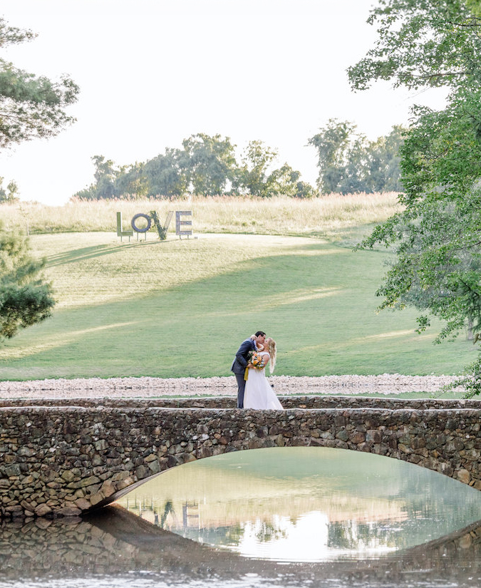 a man and woman kissing by a pond and grass