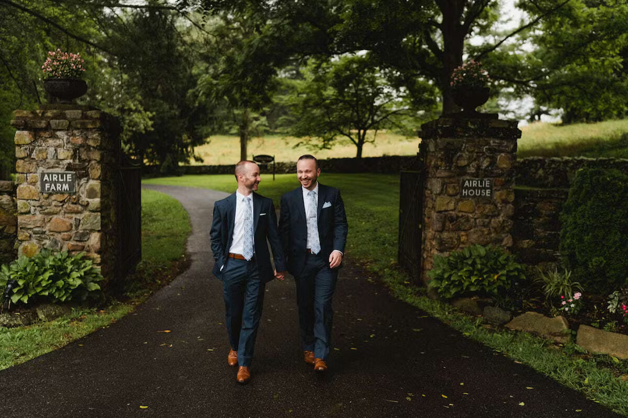two men in suits walking down a path