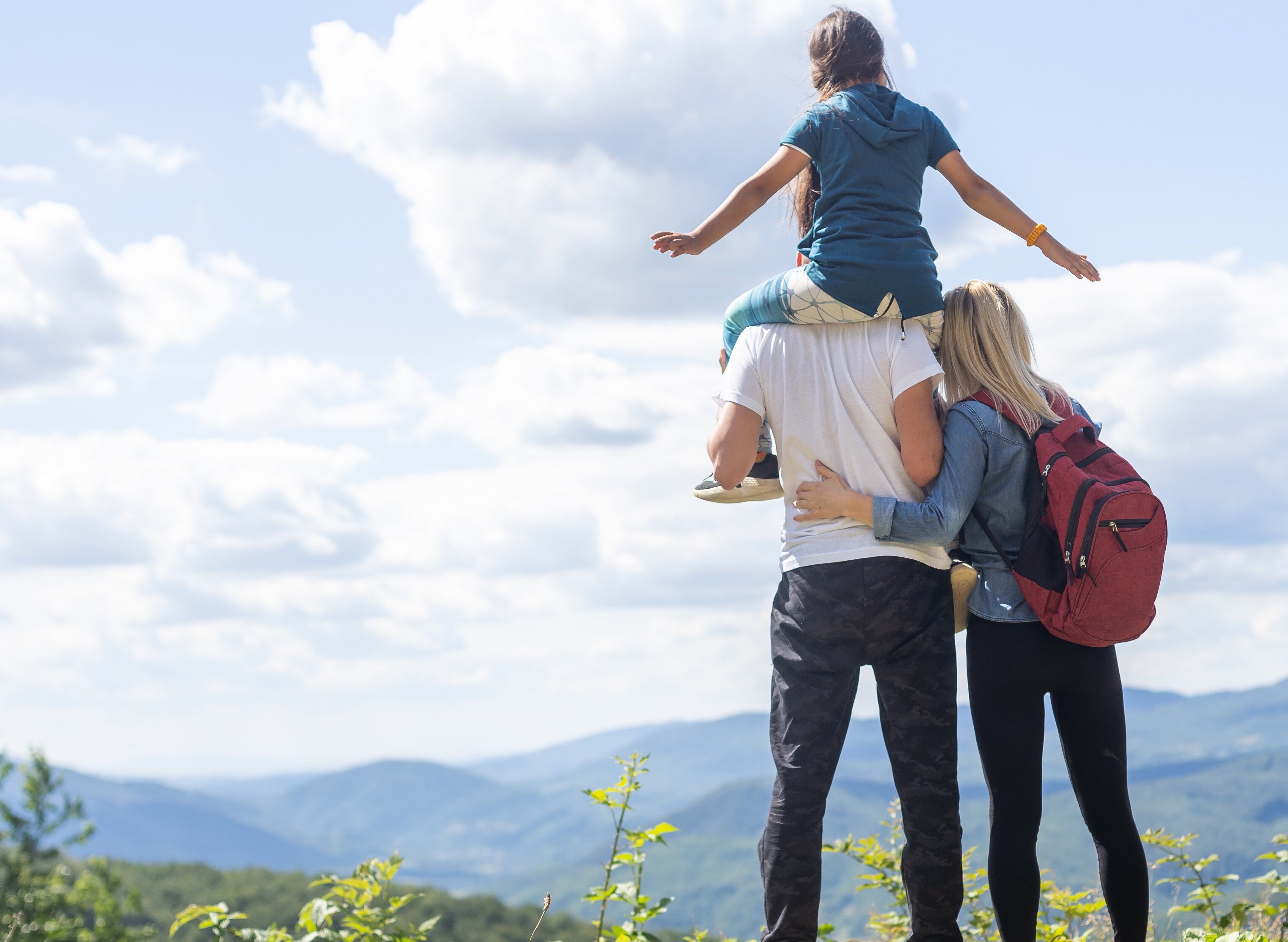 a group of people standing on a hill with a girl on top of him