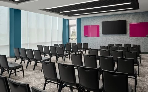 a meeting room with black chairs and a pink screen