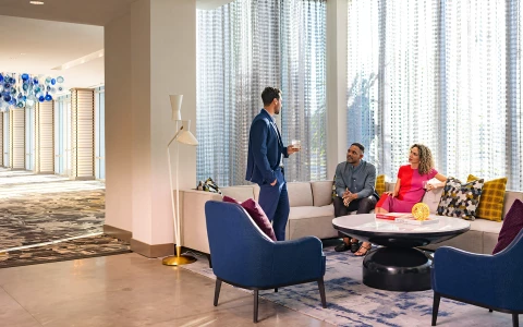 a man standing in a room with people sitting around it