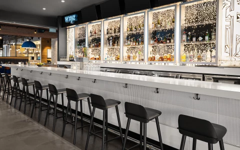 a bar with a row of stools and bottles