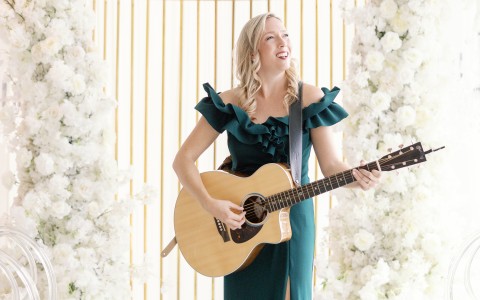 a woman in a green dress playing a guitar