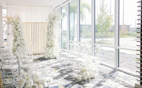 a room with white chairs and flowers