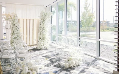 a room with white chairs and flowers
