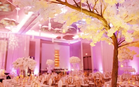 a tree with white flowers and a table set up in a room with tables and chairs