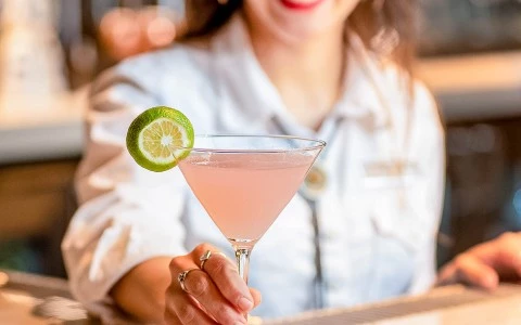 bartender handing a martini glass to customer