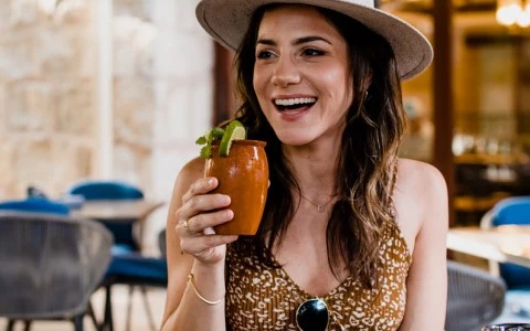 woman smiling and holding a drink