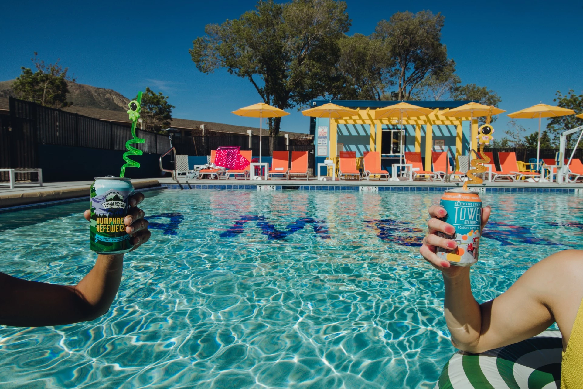 a person holding a can of soda in front of a pool