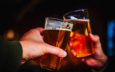 a couple of hands holding glasses of beer