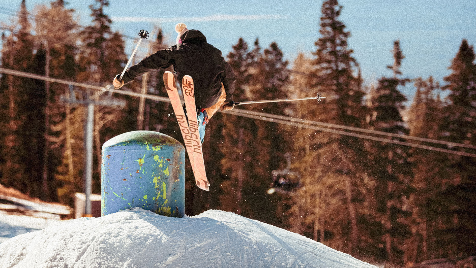 a person jumping off a snow covered hill with skis