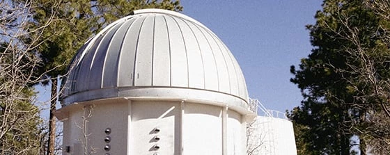 a large white building with a dome roof and trees around it