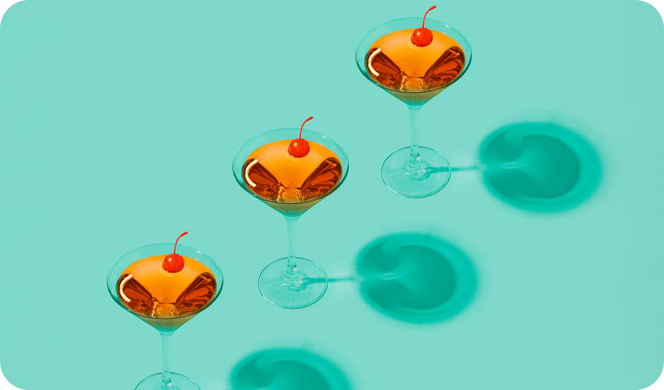 a group of glasses with orange liquid and a cherry on top