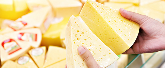 a hand holding a piece of cheese