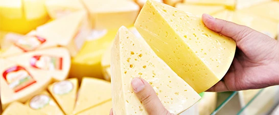 a hand holding a piece of cheese