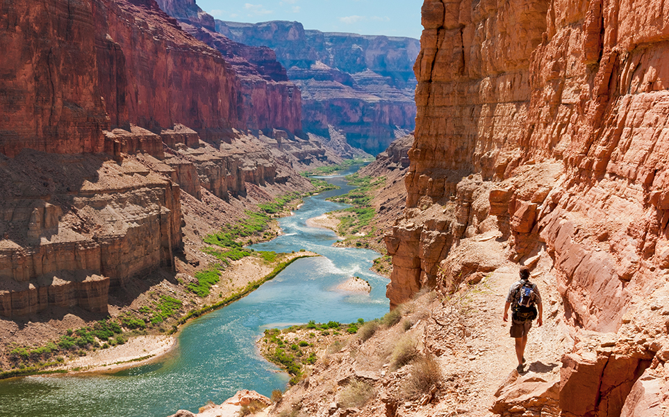 a man walking on a trail in a canyon