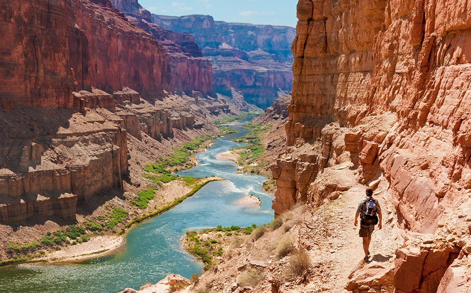 a man walking on a trail in a canyon